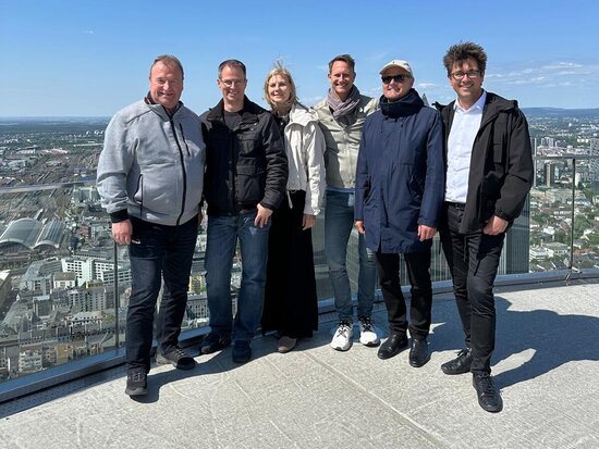 Personen auf einer Dachterrasse vor einer Skyline