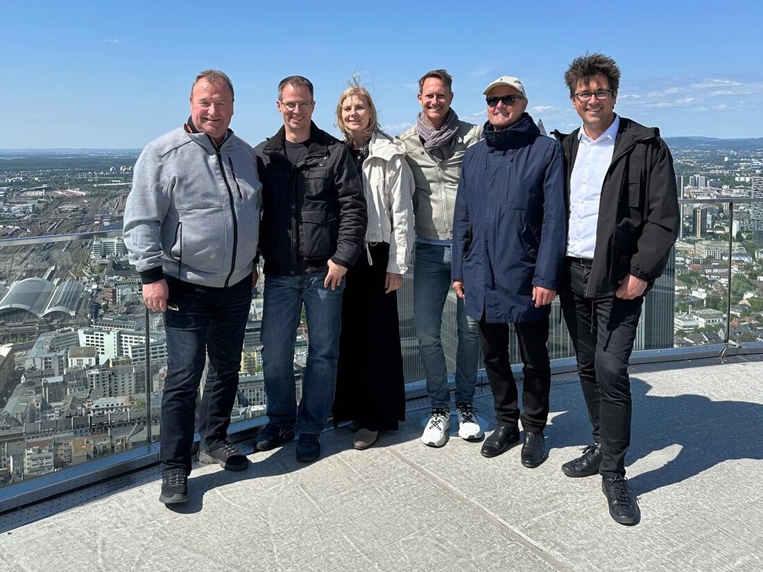 Personen auf einer Dachterrasse vor einer Skyline